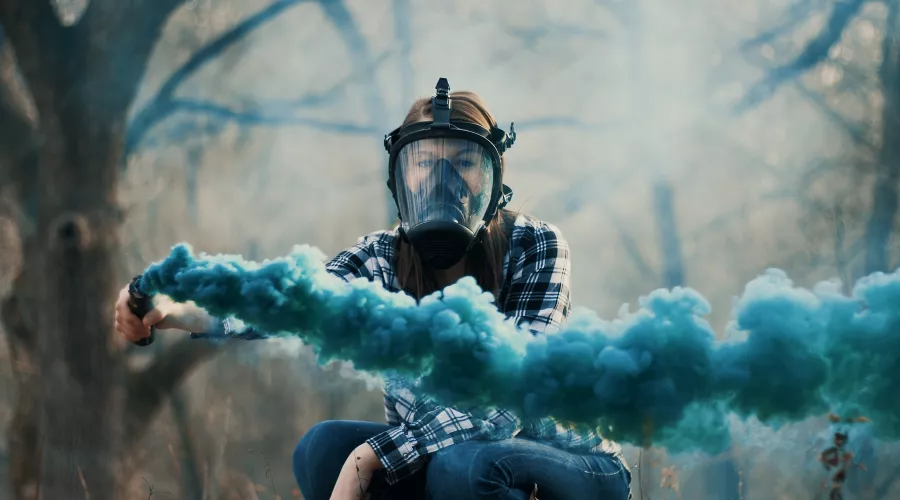 Человек в противогазе с дымовой шашкой в руке &copy;&nbsp;Фото Connor Botts, unsplash.com
